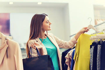 Image showing happy young woman choosing clothes in mall