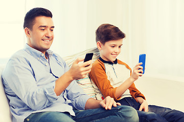 Image showing happy father and son with smartphones at home