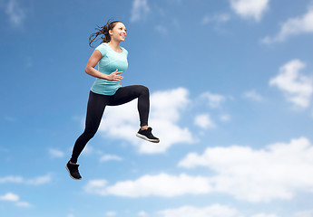 Image showing happy smiling sporty young woman jumping in air