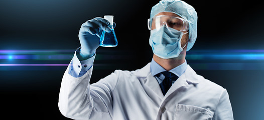 Image showing scientist in mask holding flask with chemical