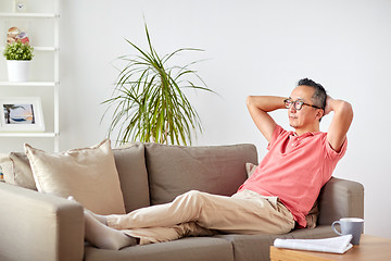 Image showing man in glasses relaxing on sofa at home