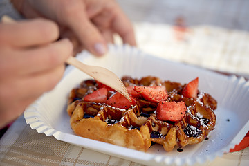 Image showing close up of woman eating waffle with strawberry