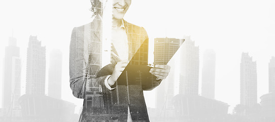 Image showing businesswoman with clipboard over city buildings