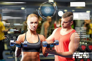 Image showing young couple with dumbbells flexing muscles in gym