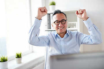 Image showing happy businessman with laptop at office