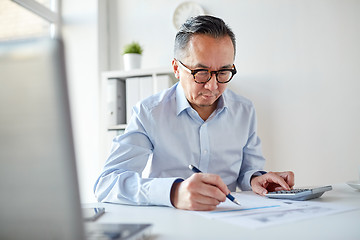 Image showing businessman with calculator and papers at office