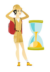 Image showing Worried asian traveler woman looking at hourglass.