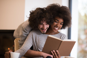 Image showing multiethnic couple hugging in front of fireplace