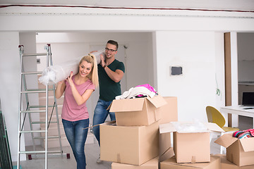 Image showing couple carrying a carpet moving in to new home