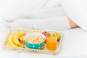 Image showing Partial view of female legs and breakfast on bed