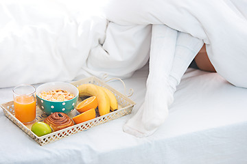 Image showing Partial view of female legs and breakfast on bed