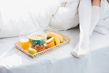 Image showing Partial view of female legs and breakfast on bed