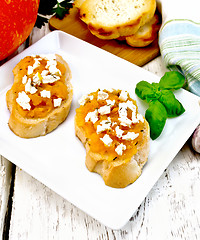 Image showing Bruschetta with pumpkin and cheese in white plate on light board