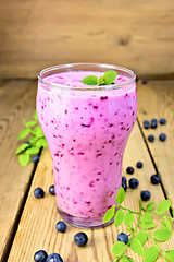 Image showing Milkshake with blueberries in glass on wooden table