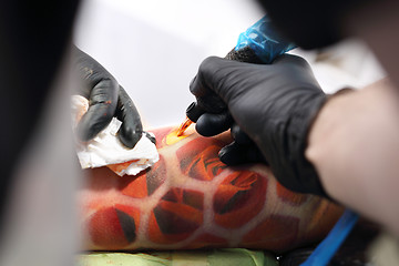 Image showing Tattooer tattooing color tattoo on his hand man