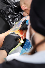 Image showing The tattoo parlor. A tattoo artist tattooing color tattoo on his hand man Tattooer tattooing color tattoo on his hand man