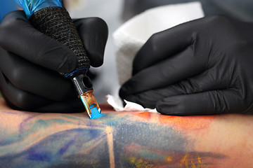 Image showing Decorating the skin tattooed. Colored tattoo on his hand. Making tattoo.