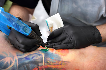 Image showing Tatoo. Tattoo artist fills the pattern in blue ink