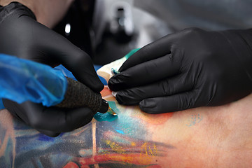 Image showing Decorating the skin tattooed. Colored tattoo on his hand.