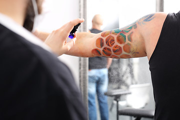 Image showing Care tattoo. A tattoo artist disinfects the customer a new drawing on the skin.