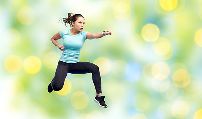 Image showing happy sporty young woman jumping in fighting pose