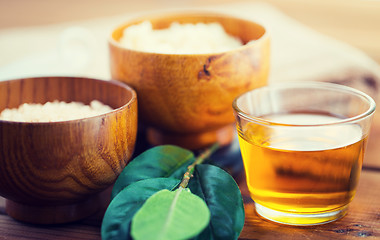 Image showing close up of honey in glass with leaves on wood