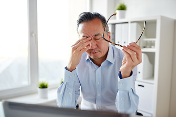 Image showing tired businessman with glasses at laptop in office