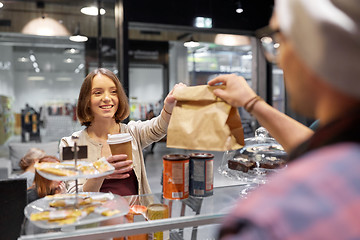 Image showing woman taking paper bag from seller at cafe