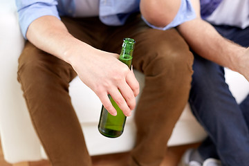 Image showing men with beer bottles sitting on sofa at home