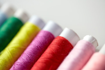 Image showing row of colorful thread spools on table