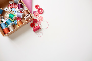 Image showing box with thread spools and sewing buttons on table