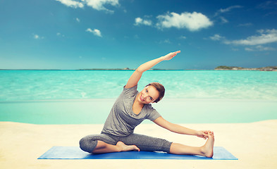 Image showing happy woman making yoga and stretching on beach 