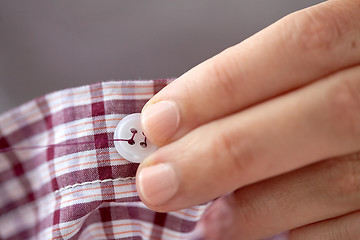 Image showing woman with needle stitching on button to shirt