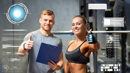 Image showing smiling young woman with personal trainer in gym