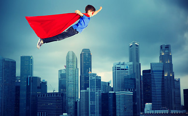 Image showing boy in red superhero cape flying over city