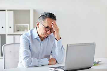 Image showing businessman in eyeglasses with laptop at office