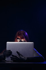 Image showing Robber in mask holds laptop