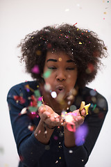 Image showing African American woman blowing confetti in the air