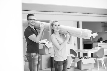 Image showing couple carrying a carpet moving in to new home