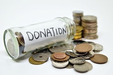 Image showing Donation lable in a glass jar with coins spilling out