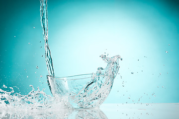 Image showing The water splashing to glass bowl on white background