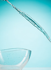 Image showing The water splashing to glass bowl on white background
