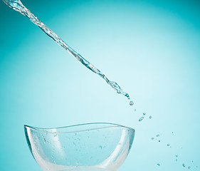 Image showing The water splashing to glass bowl on white background