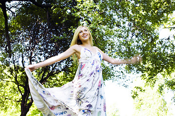 Image showing happy blond young woman in park smiling, floral close up