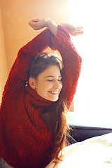 Image showing young pretty real woman in red sweater and scarf all over her fa