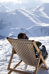 Image showing Skier at winter mountains resting on sun-lounger at nice sun day