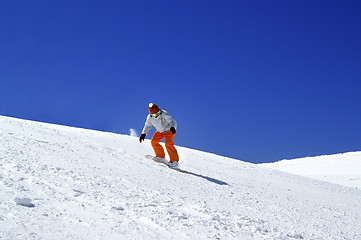 Image showing Snowboarder downhill in terrain park and blue clear sky