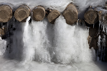 Image showing Icy mountain stream and wooden bridge frozen into ice