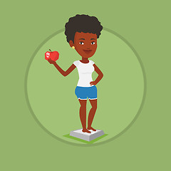 Image showing Woman standing on scale and holding apple in hand.