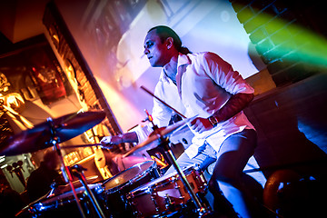 Image showing Drummer playing on drum set on stage.